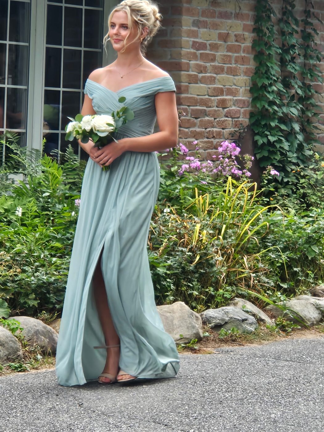 Bridesmaid with a textured low updo holding a bouquet